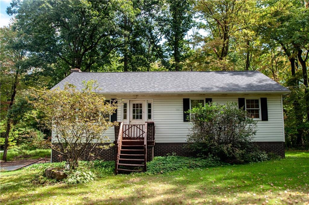 a view of a house with a yard plants and large tree