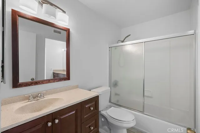 a bathroom with a shower sink vanity mirror and toilet