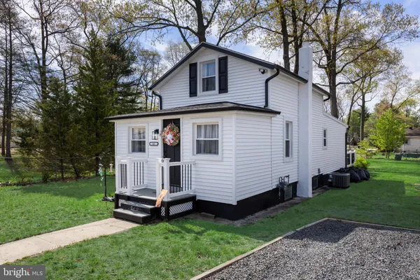 a white house that has a small yard and large trees