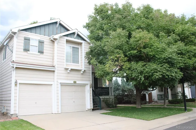 a view of a white house with a large tree and a yard