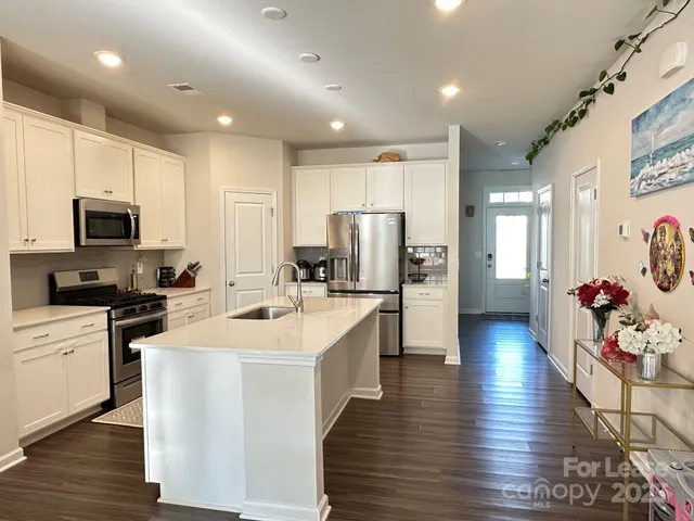 a large white kitchen with lots of counter space a sink appliances and cabinets