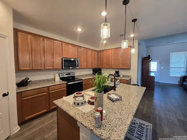 a kitchen with kitchen island granite countertop wooden cabinets a stove a oven a dining table and chairs