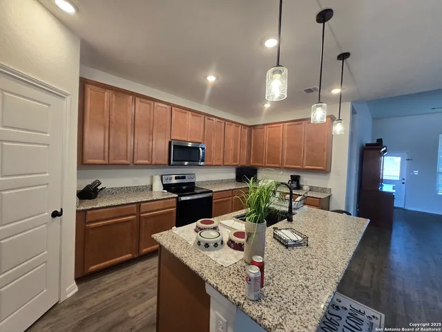 a kitchen with kitchen island granite countertop a sink a counter top space appliances and cabinets