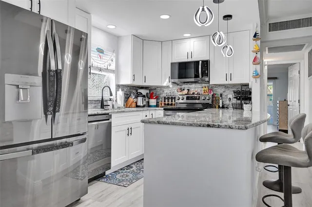 a kitchen with stainless steel appliances granite countertop a sink and a refrigerator