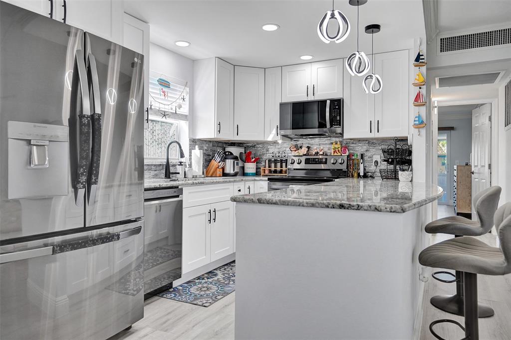 356 Brittany Avenue, Unit 356 Delray Beach, FL 33446 - Photo 1 of 31 a kitchen with stainless steel appliances granite countertop a sink and a refrigerator