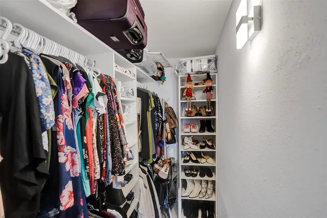 a view of walk in closet with clothes and shoes
