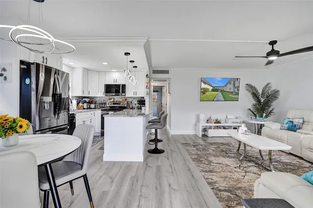 a living room with stainless steel appliances furniture and a kitchen view