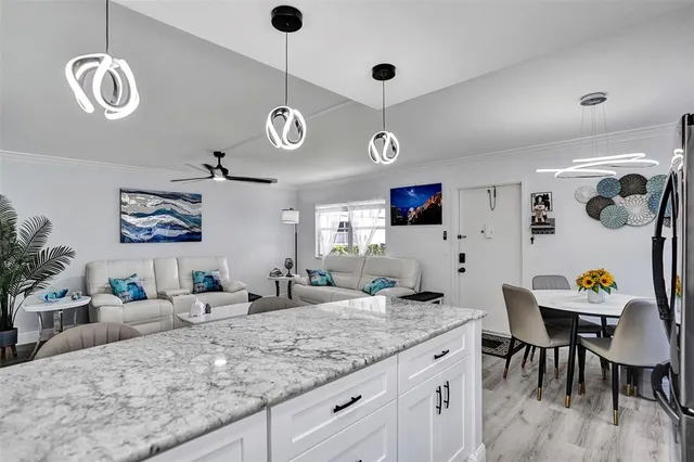 a view of a kitchen with granite countertop living room and stainless steel appliances