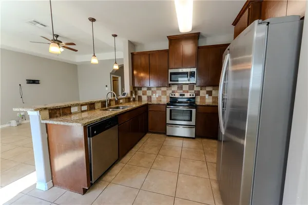 a kitchen with stainless steel appliances granite countertop a sink a stove a refrigerator and a refrigerator