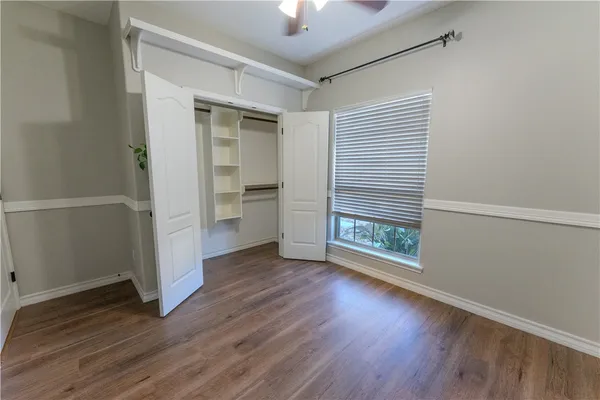 an empty room with wooden floor cabinet and windows