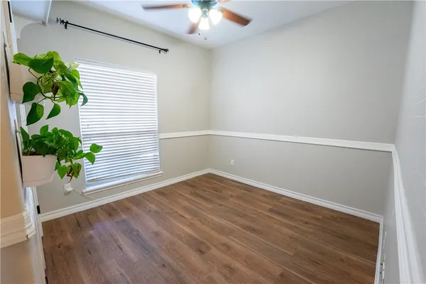 a view of an empty room with potted plant and wooden floor