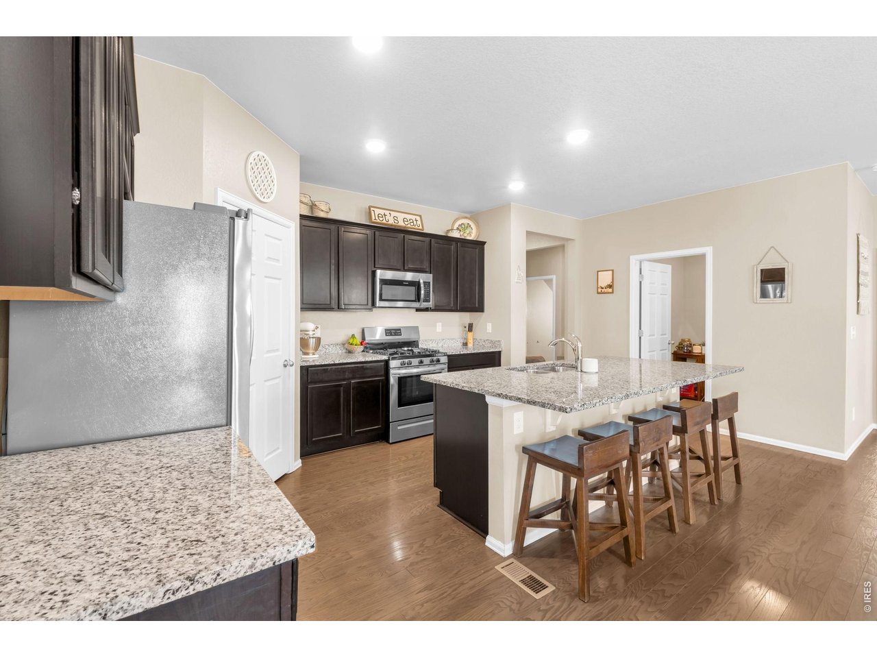 512 Buckrake Street Severance, CO 80550 - Photo 9 of 41 a kitchen with stainless steel appliances kitchen island granite countertop a refrigerator a stove a sink a dining table and chairs