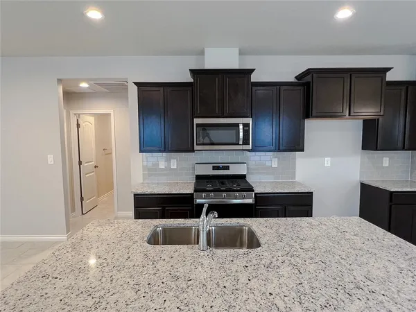 a kitchen with granite countertop a refrigerator and a sink