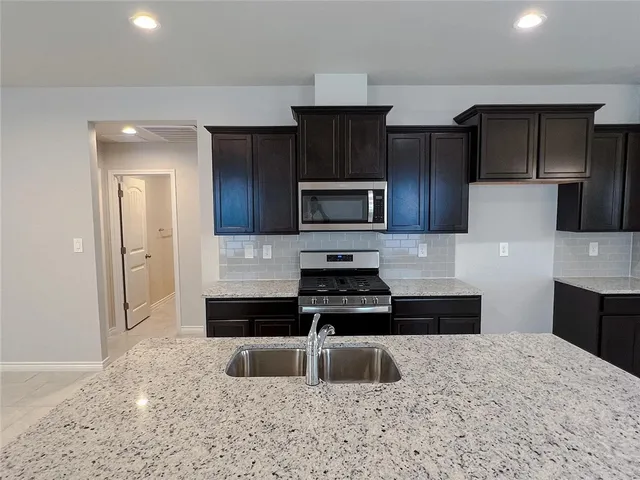 a kitchen with granite countertop a refrigerator and a sink