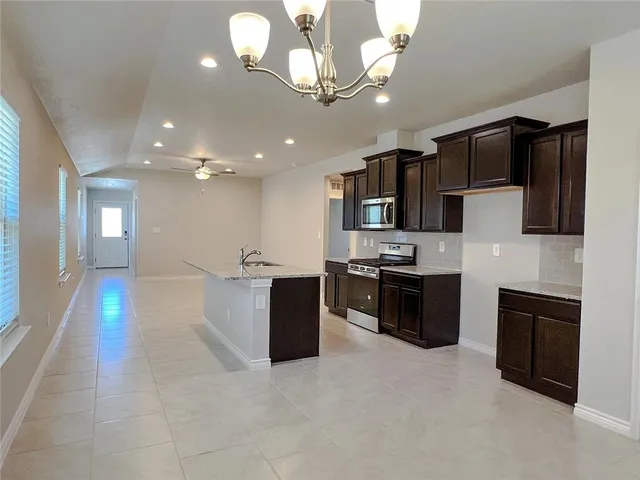 a large kitchen with stainless steel appliances kitchen island granite countertop a stove top oven a sink dishwasher a dining table and chairs with wooden floor