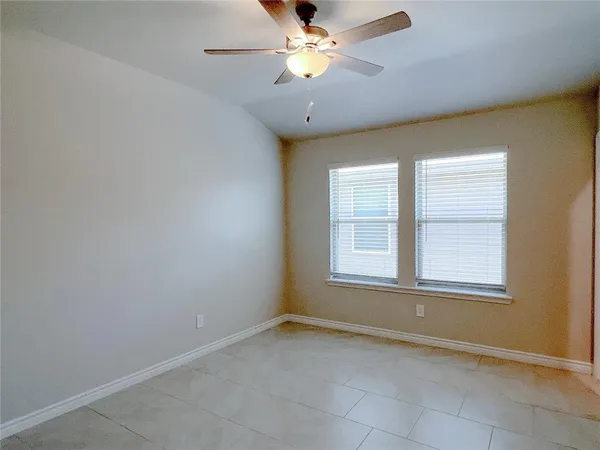 an empty room with chandelier fan and windows