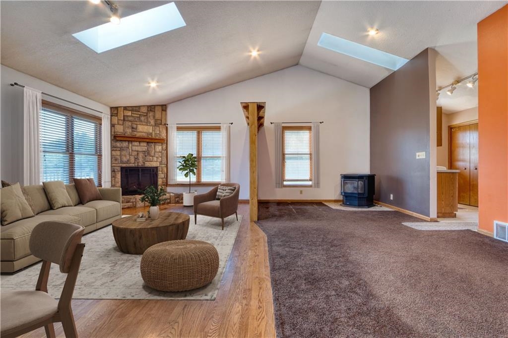 9018 North Anderson Road Hayward, WI 54843 - Photo 12 of 42 Living room with rail lighting, a wood stove, lofted ceiling, a skylight, and wood finished floors
