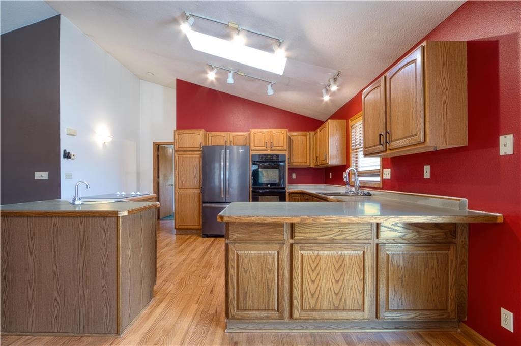 9018 North Anderson Road Hayward, WI 54843 - Photo 18 of 42 Kitchen with a peninsula, a skylight, track lighting, light wood-type flooring, and lofted ceiling