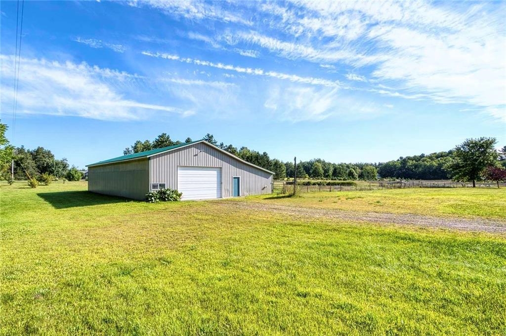 9018 North Anderson Road Hayward, WI 54843 - Photo 28 of 42 View of green lawn with an outdoor structure, a detached garage, and a rural view