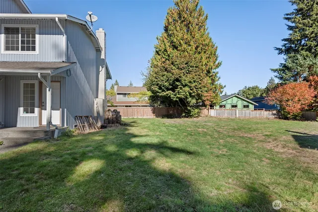 a view of a backyard with a trees and wooden fence