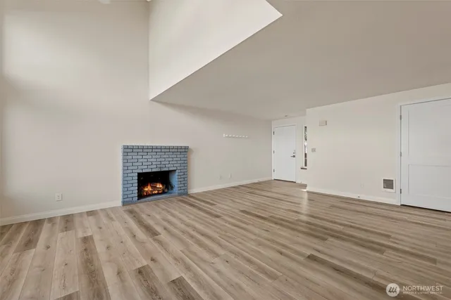 a view of empty room with wooden floor and fireplace