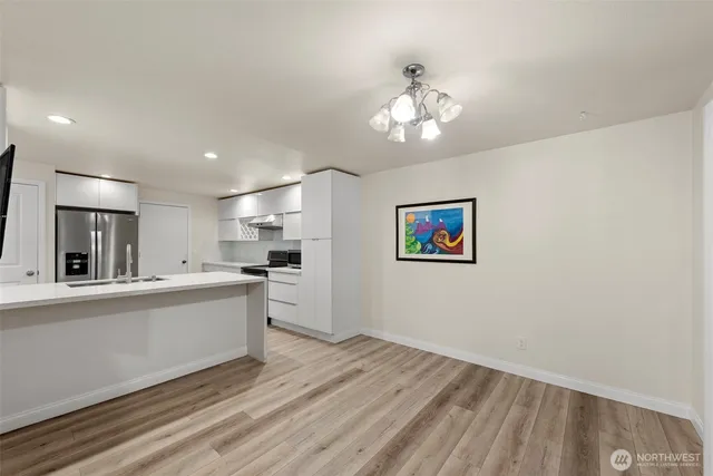 a large white kitchen with kitchen island a stove a sink dishwasher and a refrigerator with wooden floor