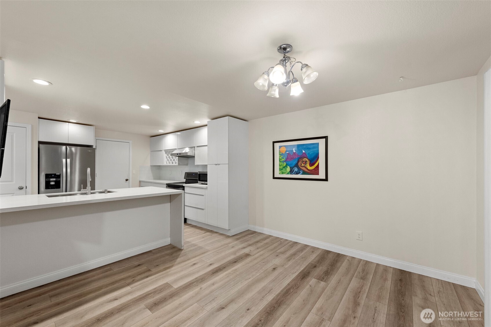 5703 134th Place Southeast, Unit A Snohomish, WA 98296 - Photo 5 of 20 a large white kitchen with kitchen island a stove a sink dishwasher and a refrigerator with wooden floor
