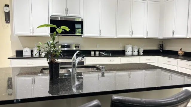 a kitchen with kitchen island granite countertop a sink a stove and a microwave