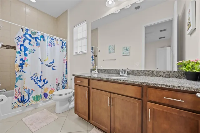 a bathroom with a granite countertop sink a toilet a mirror a vanity and shower