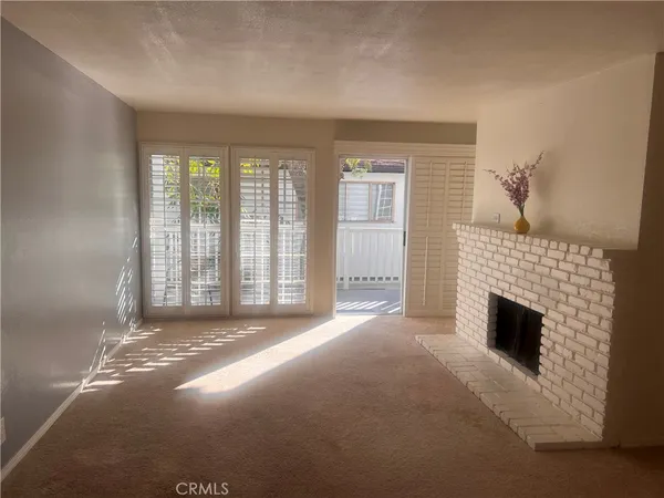 a view of an empty room with a fireplace and a window