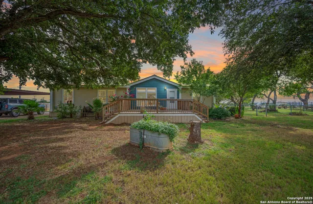 a front view of a house with a yard fire pit and large trees