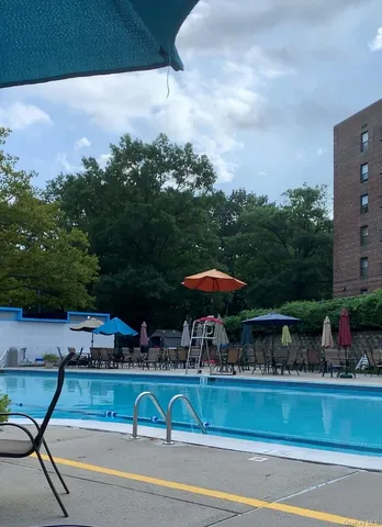 a view of a swimming pool with a table and chairs under an umbrella
