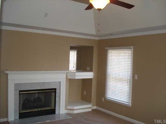 8829 Breeland Way Raleigh, NC 27613 - Photo 5 of 12 a living room with a fireplace and a ceiling fan