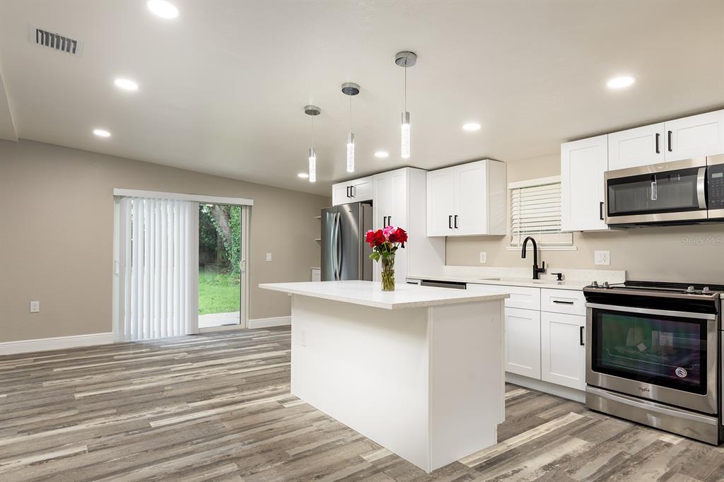 1007 San Domingo Road Orlando, FL 32808 - Photo 6 of 17 a kitchen with kitchen island granite countertop a sink cabinets and stainless steel appliances