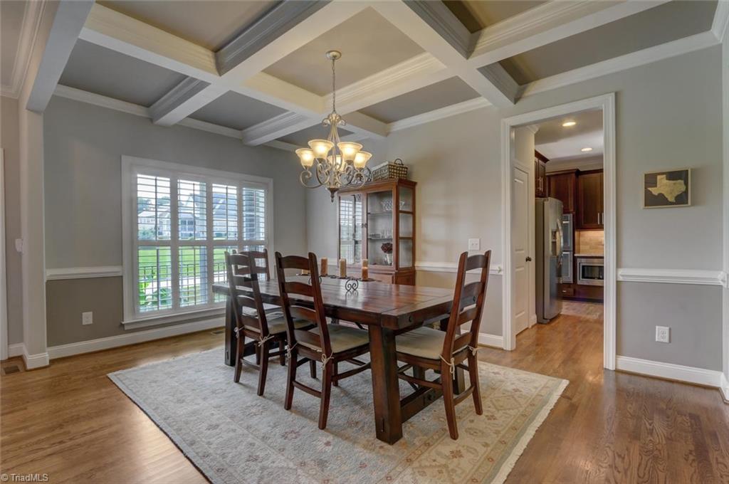 Dining room with beautiful hardwoods and coffer ceilings, plantation shutters and wainscoting in the dining room. 