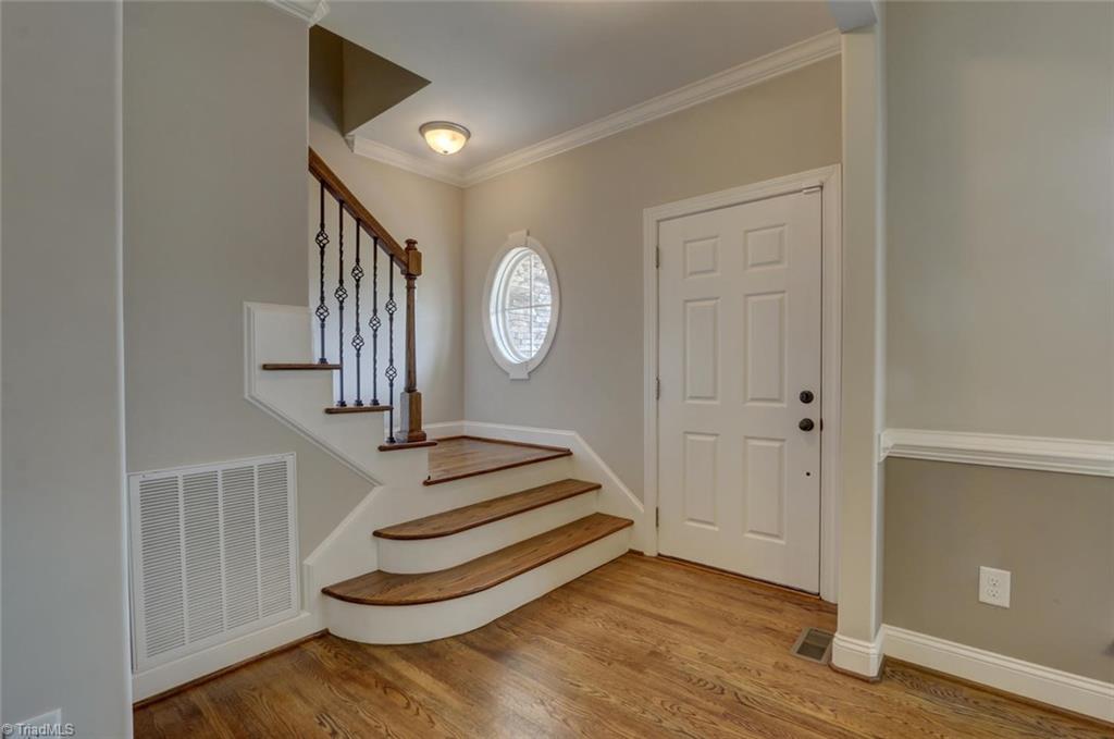 Foyer with details such as the oval widow to allow natural light. Hardwoods on the treads and iron railings. 