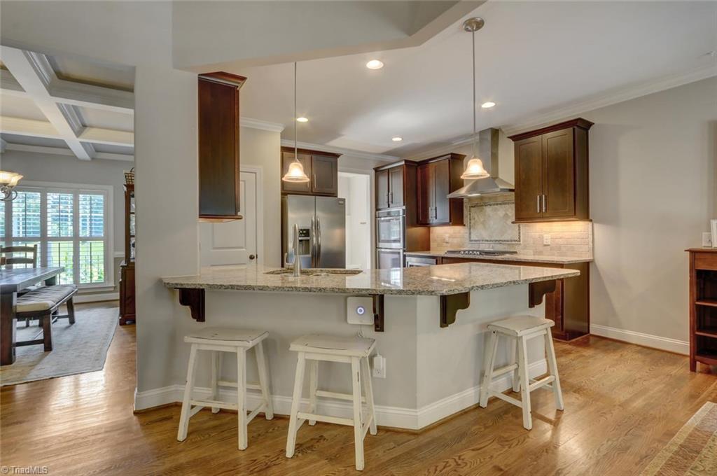 7772 Sutter Road Greensboro, NC 27455 - Photo 8 of 30 Fantastic kitchen layout! Recessed lighting, granite counter tops featuring this return bar top area that is perfect for entertaining.