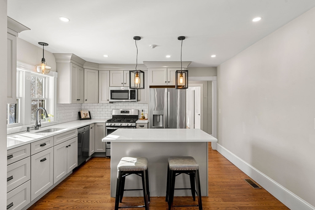 201 Main Street Rowley, MA 01969 - Photo 10 of 42 a kitchen with stainless steel appliances granite countertop a sink a stove a refrigerator and island with wooden floor