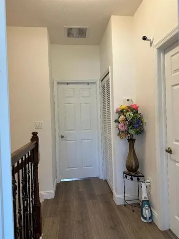 a view of a hallway with wooden floor and a potted plant