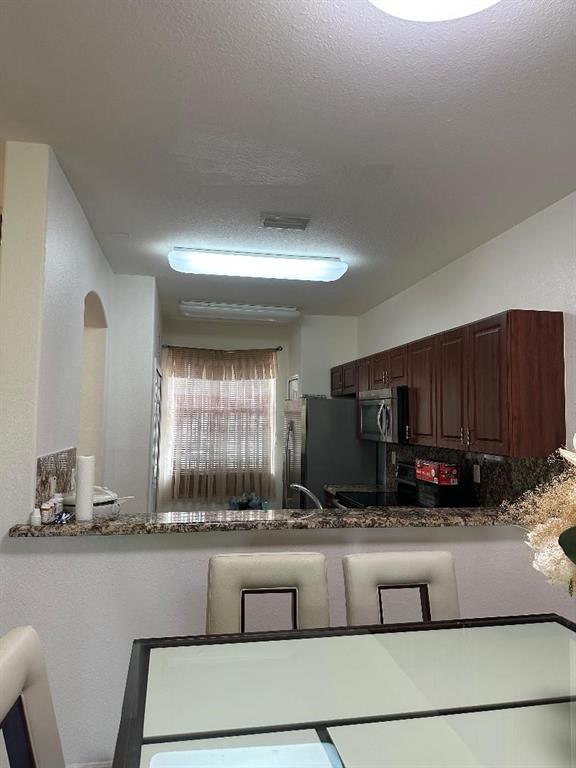 8824 Southwest 153rd Court Miami, FL 33196 - Photo 7 of 25 a kitchen with granite countertop a stove a sink and a wooden cabinets