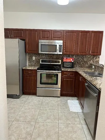 a kitchen with granite countertop a stove top oven cabinets and stainless steel appliances