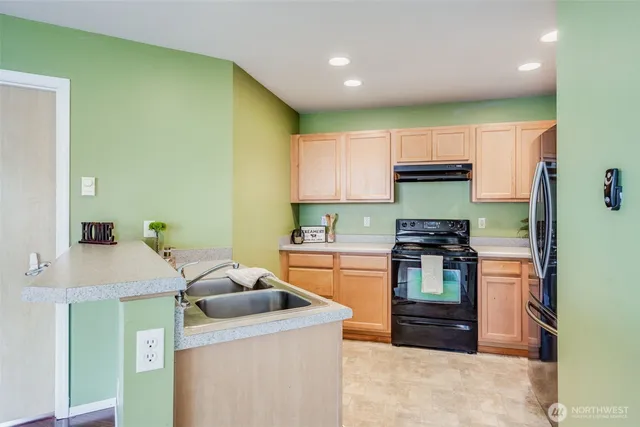 a kitchen with stainless steel appliances granite countertop a refrigerator sink and stove