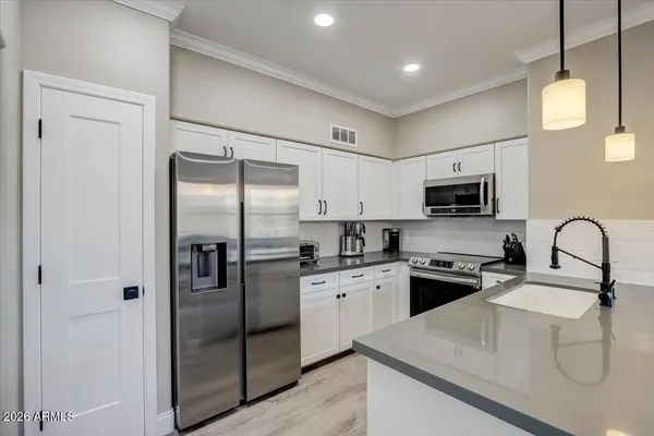 a kitchen with stainless steel appliances granite countertop a sink a stove a refrigerator cabinets and a dining table with wooden floor