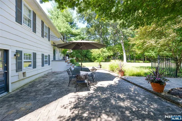 a swimming pool that is in front of the house with large trees