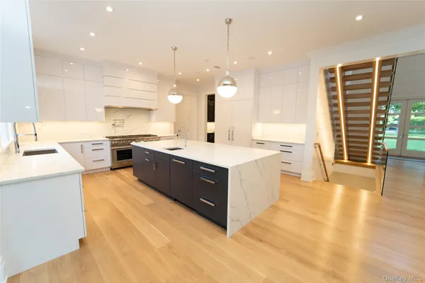 a large kitchen with a large counter top a sink a counter space and stainless steel appliances