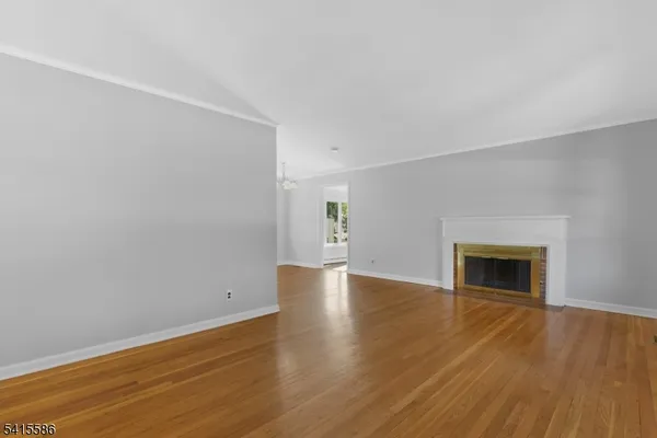a view of empty room with wooden floor and fireplace
