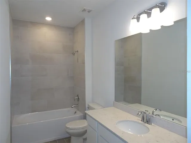 a bathroom with a granite countertop sink a toilet and shower