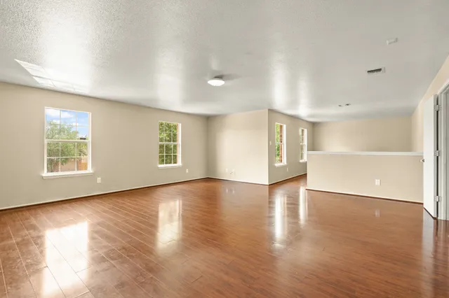 a view of an empty room with window and wooden floor