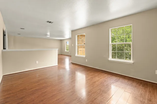 an empty room with wooden floor and windows