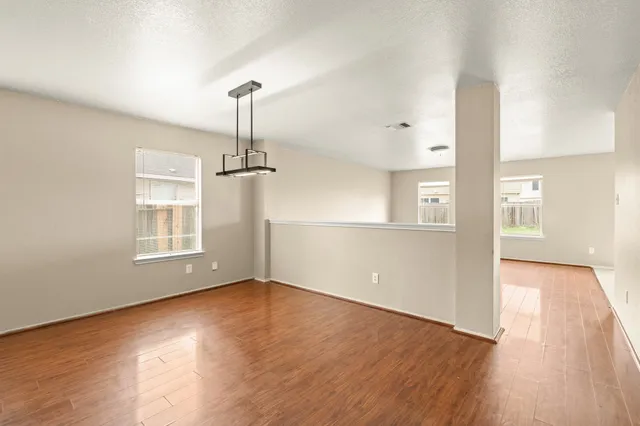 a view of empty room with wooden floor and fan